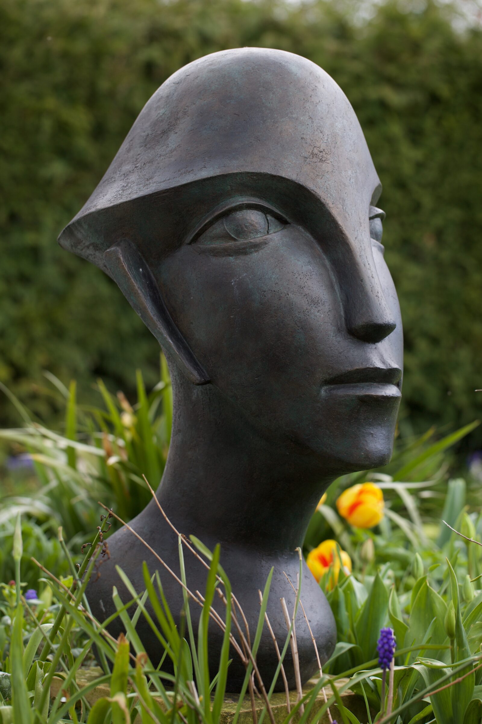 Racer Man 2 Bronze Resin 90 x 40 x 55cm with tulips modern bronze sculpture of a very large head in spring garden